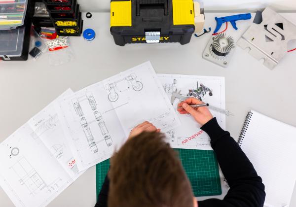 Man drawing engineering designs on table