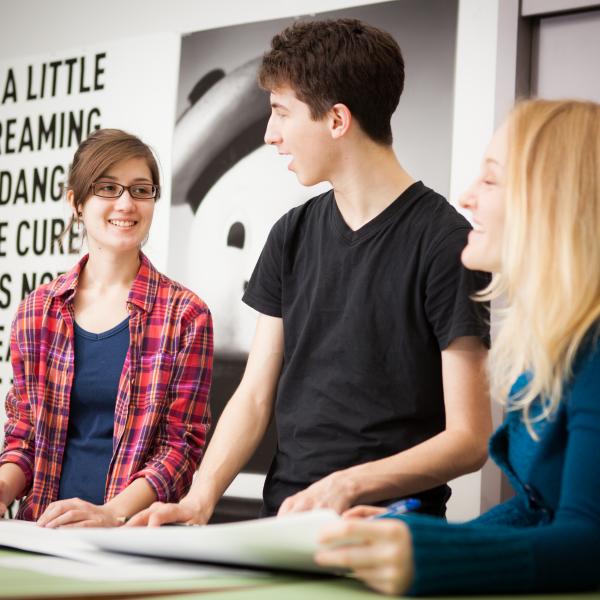 3 Graphic Design students standing in a classroom and talking