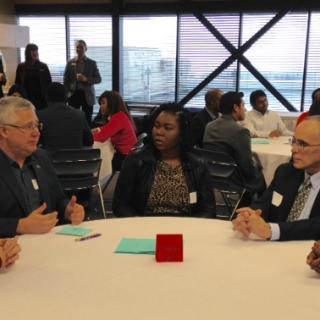 A group of students and employers talking at a table during the LMRT